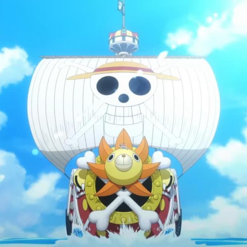 Puede incluir: Un barco blanco y rojo con un dise&ntilde;o de calavera y huesos cruzados en la vela. El barco tiene un sol amarillo con una cara en la parte delantera.