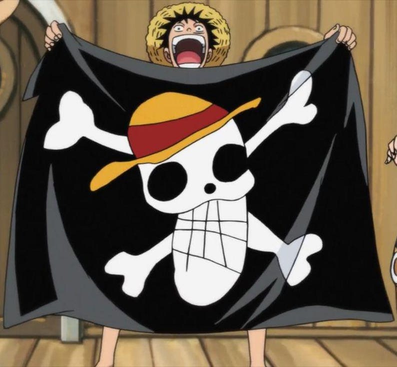 Puede incluir: Una bandera pirata negra con una calavera blanca y huesos cruzados. La calavera lleva un sombrero de paja amarillo y rojo.