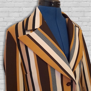 May include: A striped blazer with brown, beige and white stripes. The blazer has a double-breasted closure and a pointed collar.