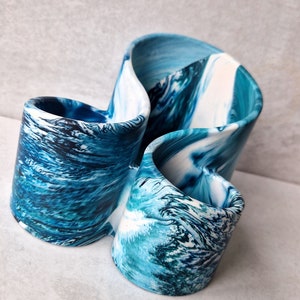 May include: A blue and white ceramic vase with a swirled design. The vase is shaped like a figure of eight and has two openings.