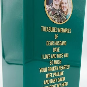 May include: A rectangular dark green memorial plaque featuring a circular photograph of a person in military uniform and a woman. The plaque displays gold text reading: TREASURED MEMORIES OF DEAR HUSBAND DAVE I LOVE AND MISS YOU SO MUCH YOUR BROKEN HEARTED WIFE PAULINE AND BABY DAVID SLEEP TIGHT MY HERO XX.