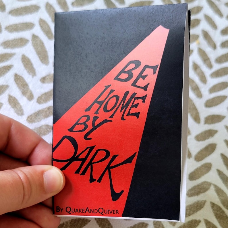 May include: A black and red book cover with the text "BE HOME BY DARK" in white lettering. The text is on a red background with a black border. The book title is "BE HOME BY DARK" by "QUAKEANDQUIVER".