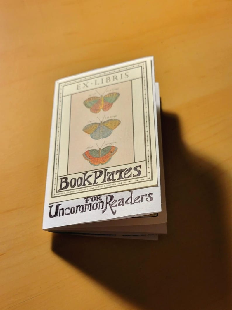 May include: A small book with a white cover and a black border. The cover features a vintage illustration of three butterflies and the text "Ex-Libris Book Plates for Uncommon Readers".