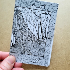 May include: A black and white illustration of a forest path with trees on either side. The title "A WALK" is written in black at the top of the image. The image is printed on a white background with a blue dotted border.