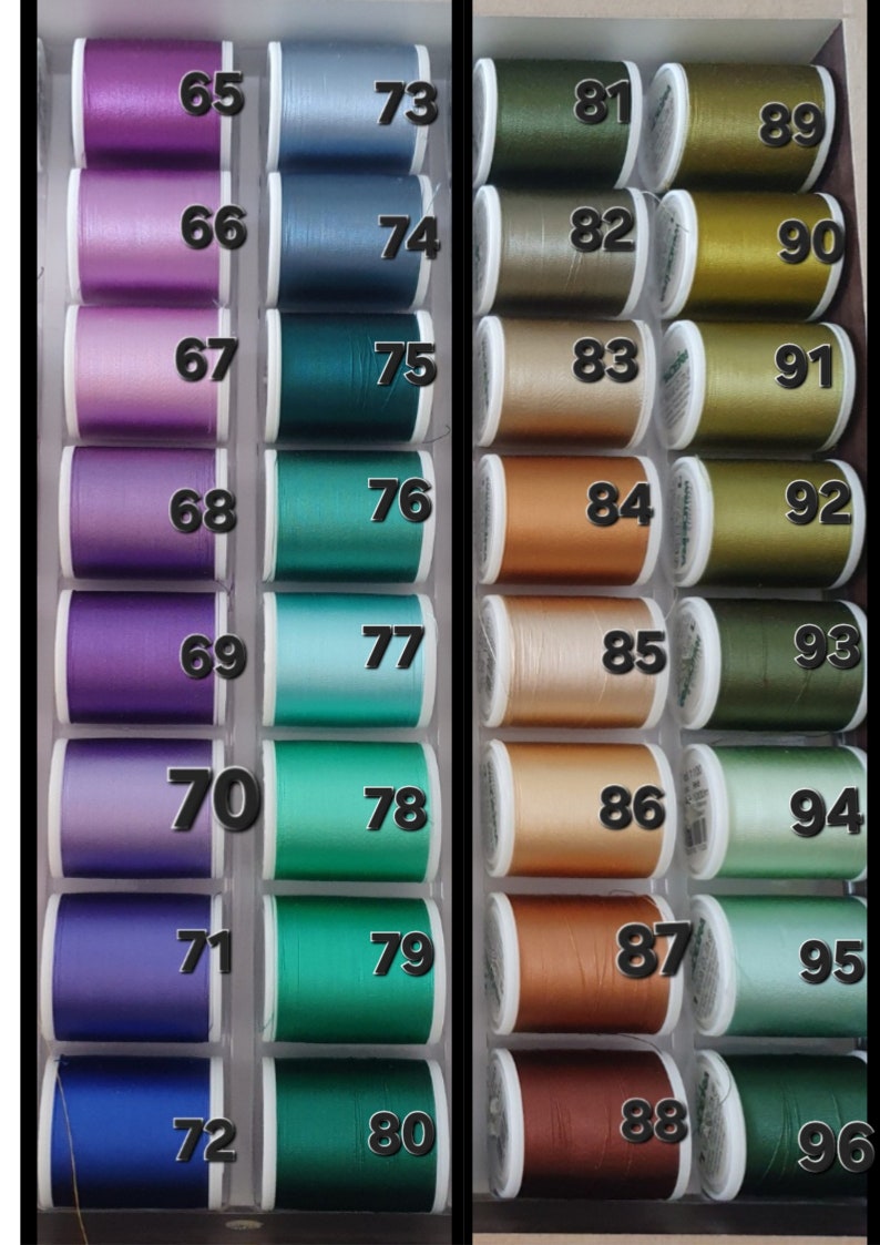 May include: A collection of spools of thread in various colors, arranged in a display case. The spools are labeled with numbers from 65 to 96, with shades of purple, blue, green, gold, and brown. Ideal for sewing and crafting projects.