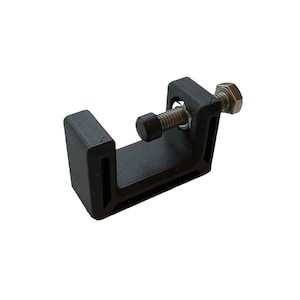 May include: A black plastic clamp with a silver screw and nut. The clamp is designed to hold objects in place.