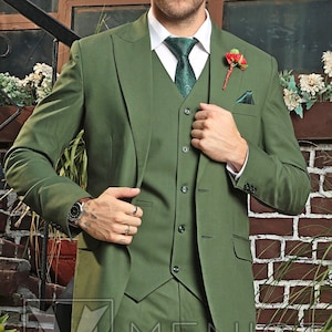 Puede incluir: Un traje de tres piezas en color verde oscuro. El traje incluye una chaqueta, un chaleco y pantalones. El hombre lleva una corbata verde oscuro y zapatos de cuero marr&oacute;n.