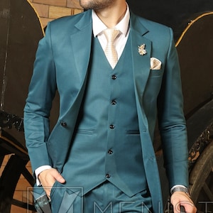 May include: A teal three-piece suit with a vest and a matching tie. The suit is worn by a person standing next to a black carriage with wooden wheels. The person is holding a black umbrella.