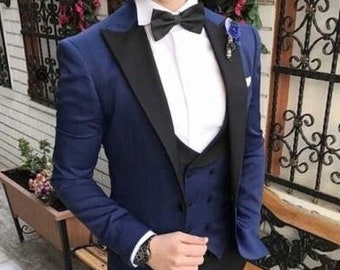 May include: A blue tuxedo jacket with a black satin lapel, a white dress shirt with a black bow tie, a black vest, and black pants. The man is wearing black patent leather shoes.