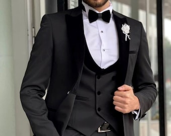 May include: A black tuxedo suit with a velvet lapel and a white shirt with a bow tie. The suit includes a matching waistcoat.