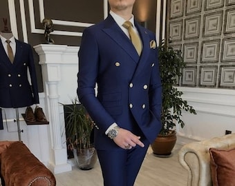 Può includere: Un abito blu navy doppiopetto con bottoni dorati. La giacca ha un revers a punta e i pantaloni hanno una gamba dritta.
