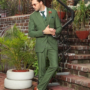 Puede incluir: Un hombre con un traje verde de tres piezas con un cintur&oacute;n de cuero marr&oacute;n y zapatos de cuero marr&oacute;n. Est&aacute; de pie en una escalera de ladrillo con una planta verde en una maceta blanca detr&aacute;s de &eacute;l.