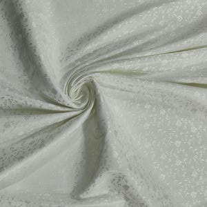 May include: Ivory-colored fabric with a subtle floral pattern. The fabric is draped, creating soft folds and shadows. The delicate design adds texture and visual interest to the material, suitable for apparel or home decor projects.