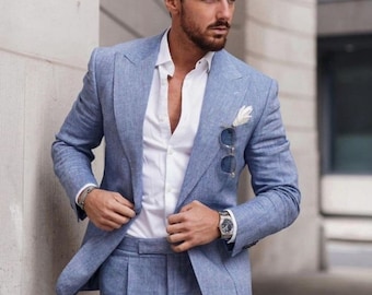 May include: A light blue linen suit with a white button-down shirt. The suit jacket has a pocket square and the man is wearing a watch.