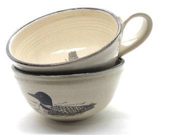 Könnte beinhalten: Zwei weiße Keramikschalen mit einem schwarz-weißen Seeadler-Design. Die obere Schale hat einen Henkel.