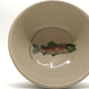 May include: A white ceramic bowl with a green and pink fish design.