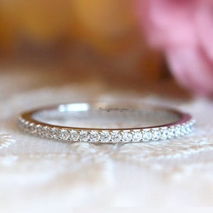 Puede incluir: Una fina banda de plata con una fila de pequeños diamantes transparentes engastados en pavé.