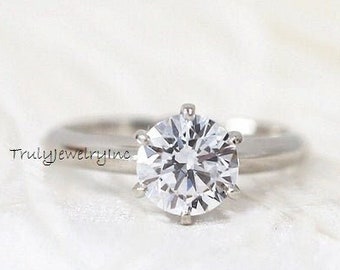May include: A silver ring with a large, round, clear diamond solitaire.
