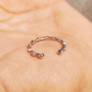 May include: A silver ring with small, clear stones set in a circular pattern.
