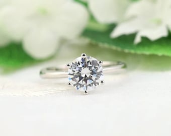 May include: A silver ring with a large, round, clear diamond.