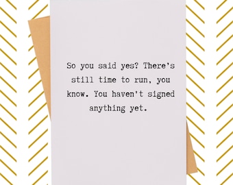 May include: A white card with a humorous message about saying "yes" to a proposal. The text reads: "So you said yes? There's still time to run, you know. You haven't signed anything yet."