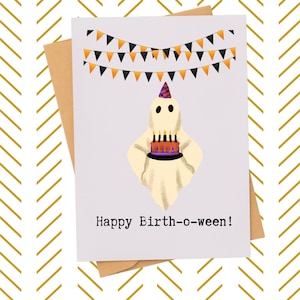 May include: A Halloween-themed greeting card with a cartoon ghost holding a birthday cake. The ghost wears a party hat and is under a banner of orange and black pennants. The card reads "Happy Birth-o-ween!" and is paired with a brown envelope.