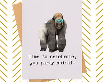 May include: Greeting card featuring a gorilla wearing teal glasses. The gorilla is gray and brown with a white patch on its back. The card reads, "Time to celebrate, you party animal!" The card is on a brown envelope.