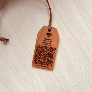 May include: A wooden tag with a leather cord. The tag has a Wi-Fi symbol, network and password information, and a QR code. The text "SCAN TO CONNECT" is at the bottom of the tag. The tag is a light brown color.