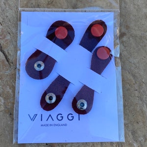 May include: Four burgundy leather shoe laces with silver eyelets and red accents. The laces are packaged on a white card with the text "VIAGGI MADE IN ENGLAND".