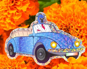 May include: A blue and silver glitter sticker of a blue Volkswagen Beetle with a masked driver. The car is driving on a road with a green and white flag on the back. The sticker is surrounded by orange marigold flowers.