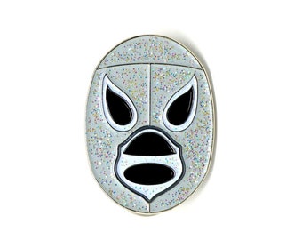 May include: A silver glitter luchador wrestling mask pin with black and white details. The mask has a classic luchador design with a pointed top and a wide, open mouth.