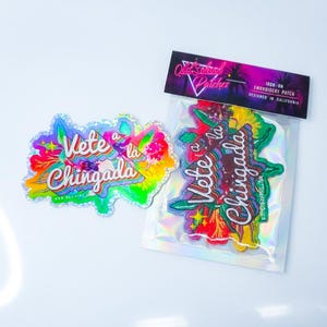 May include: Two patches with the phrase "Vete a la Chingada" in a colorful, floral design. One is a sticker, the other is an iron-on patch. The iron-on patch is packaged with a label that reads "Old School Patches".