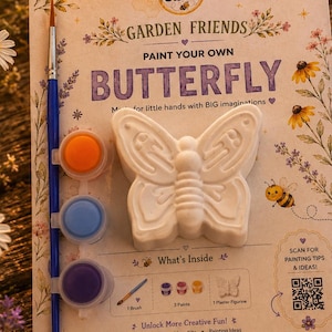 May include: A Busy Beez paint your own butterfly kit featuring a white plaster butterfly figurine, a blue paintbrush, and three small paint pots in orange, blue, and purple. The packaging includes text, a QR code, and floral illustrations.