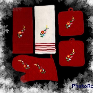 May include: Set of five red kitchen towels with floral embroidery. The set includes two hand towels, two pot holders, and one oven mitt.