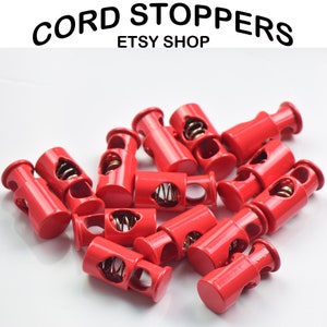 May include: A group of red plastic cord stoppers with a metal spring inside. The stoppers are designed to secure cords and prevent them from fraying.