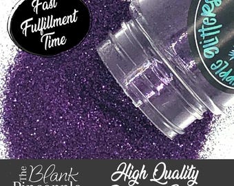 May include: Purple polyester glitter in a clear jar with a black label that says "Purple Glitter". The glitter is spilling out of the jar onto a white surface. The text "Fast Fulfillment Time" is on a black circle in the upper left corner of the image. The text "The Blank Pineapple" and "High Quality Polyester Glitter" are at the bottom of the image.