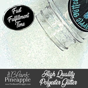 Puede incluir: Un frasco transparente de purpurina blanca con una etiqueta negra que dice "The Blank Pineapple Glitter". La etiqueta también tiene un gráfico de piña y el texto "High Quality Polyester Glitter".