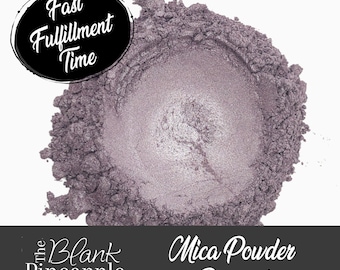 Può includere: Primo piano di un mucchio di pigmento in polvere di mica viola. La polvere è di colore viola chiaro con un leggero luccichio. Il testo "The Blank Pineapple" e "Mica Powder Pigment" è visibile nella parte inferiore dell'immagine.