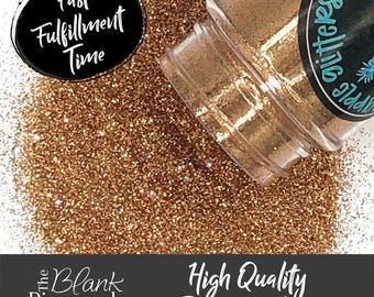 May include: A close-up of a jar of copper glitter, with the glitter spilling out onto a white surface. The jar has a black label with the text "The Blank Pineapple Glitter" and "Fast Fulfillment Time".