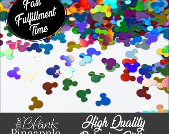 May include: A close-up of iridescent rainbow Mickey Mouse head shaped glitter. The glitter is scattered on a white surface. The text "Fast Fulfillment Time" is in a black circle at the top of the image. The text "The Blank Pineapple" is in a black rectangle at the bottom left of the image. The text "High Quality Polyester Glitter" is in a black rectangle at the bottom right of the image.