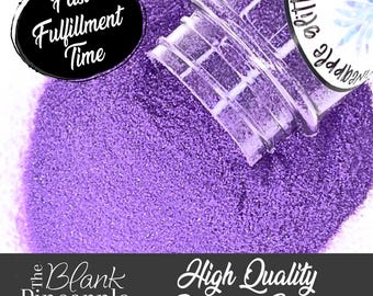 May include: A close-up of a jar of purple polyester glitter. The jar is tipped over, spilling the glitter onto a white surface. The text "High Quality Polyester Glitter" is visible in the image.