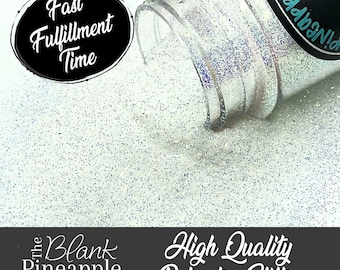 May include: A clear jar of iridescent white glitter is pouring out onto a white surface. The jar has a black label with the text "The Blank Pineapple" and a pineapple graphic. The text "High Quality Polyester Glitter" is also visible on the surface.