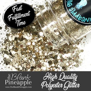 May include: A close-up of a small jar of gold glitter. The jar is tipped over, spilling the glitter onto a white surface. The jar has a label that says "The Blank Pineapple" and "High Quality Polyester Glitter".