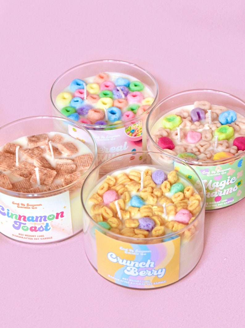 May include: Four different scented candles in glass jars with various cereal-themed designs. The candles are labeled "Cinnamon Toast", "Cereal Milk", "Crunch Berry", and "Magic Charms".