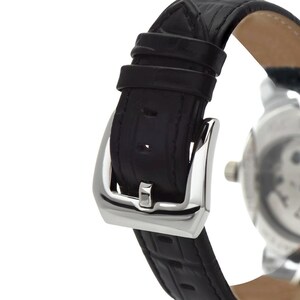 May include: Close-up of a black leather watch strap with a silver buckle. The strap has a textured, embossed pattern. The watch face is partially visible in the background, suggesting a classic timepiece.