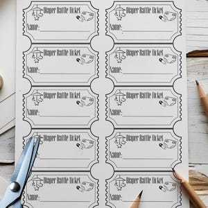 May include: A white sheet of paper with eight "Diaper Raffle Ticket" templates printed in black ink. Each ticket has a space for a name and a small diaper graphic. Scissors and pencils are in the image.