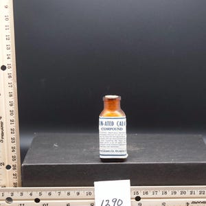 May include: A small amber glass bottle with a white label that reads "IN-ATED CALO COMPOUND" and "CALOMEL CO. ATLANTA".