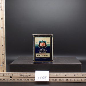 May include: A blue and gold metal spice tin with the text "IGA Brand Pure Ground Spices Cayenne 2 oz. Net" printed on the front.