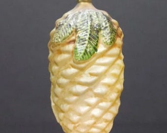 May include: A white glass Christmas ornament shaped like a pine cone with green leaves.