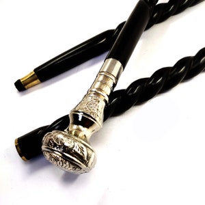 May include: A black walking stick with a silver, ornate handle. The stick is twisted and has a black rubber tip.